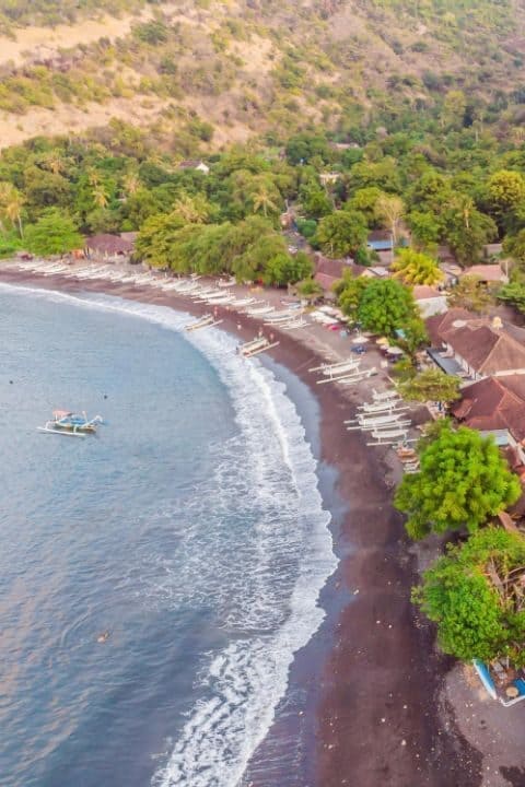 aerial-view-amed-beach-bali-indonesia-traditional-fishing-boats-called-jukung-black-sand-beach-mount-agung-volcano-background-partially-covered-by-clouds